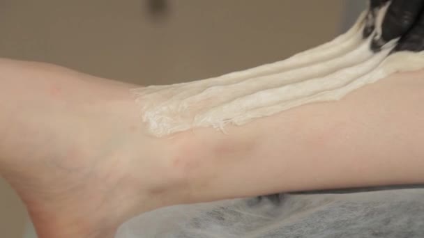 Esteticista faz shugaring nas pernas de uma jovem mulher . — Vídeo de Stock