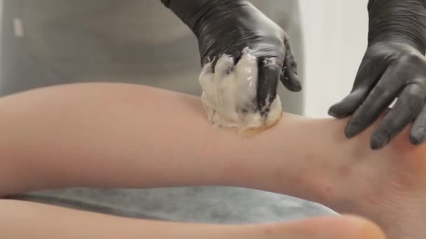 Косметолог робить шугарінг на ногах молодої жінки . — стокове відео