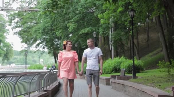 Piękni kochankowie spacerują po parku trzymając się za ręce. — Wideo stockowe