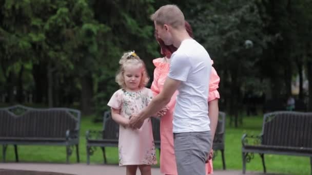 Eine junge Familie mit Kind spaziert am Brunnen. — Stockvideo