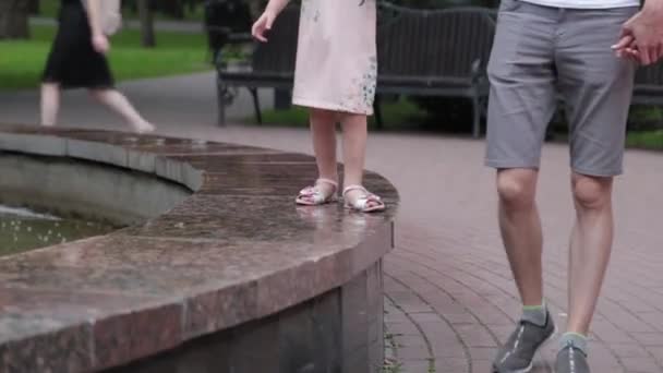 Una familia joven con un niño camina junto a la fuente . — Vídeos de Stock