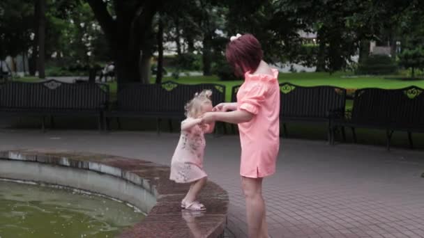 Ibu yang bahagia dengan seorang anak di air mancur. — Stok Video