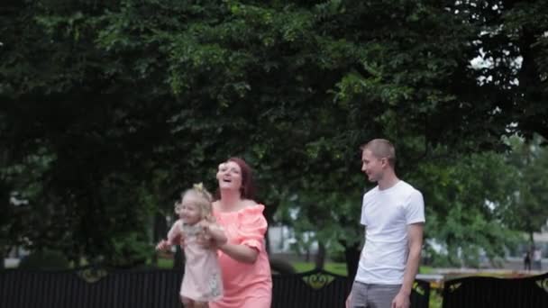 En ung familj med ett barn går vid fontänen. — Stockvideo