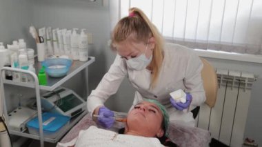 Profesyonel güzellik uzmanı bir kadına yüz maskesi takıyor..