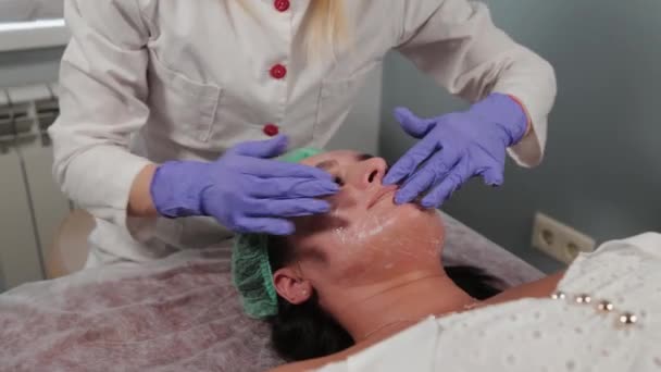 Esteticista profesional lava a una mujer y masajea su cara . — Vídeo de stock