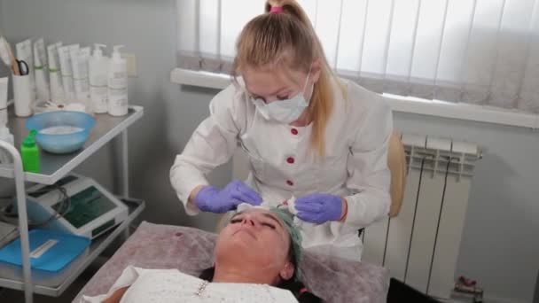 Esteticista profesional lava la máscara de la cara de una mujer . — Vídeo de stock