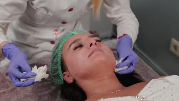 Professionele schoonheidsspecialiste wast het masker van het gezicht van een vrouw. — Stockvideo