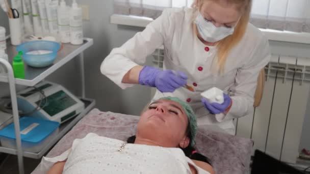 Profesjonalny kosmetyk nakładający maskę na twarz kobiecie. — Wideo stockowe