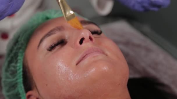 Professionelle Kosmetikerin trägt einer Frau eine Gesichtsmaske auf. — Stockvideo