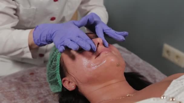 전문적 인 미용사가 여자를 닦고 얼굴을 마사지 한다. — 비디오