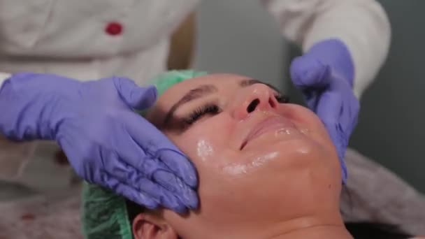 전문적 인 미용사가 여자를 닦고 얼굴을 마사지 한다. — 비디오
