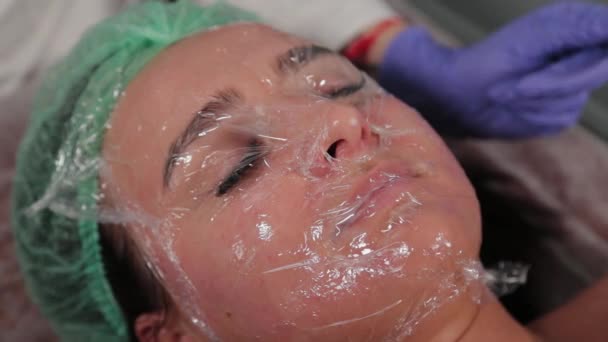 Професійний косметолог наносить плівку на обличчя . — стокове відео