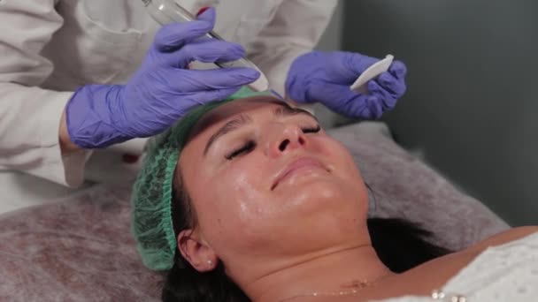 Donna cosmetologa professionista che fa pulizia del viso ad ultrasuoni al paziente. — Video Stock