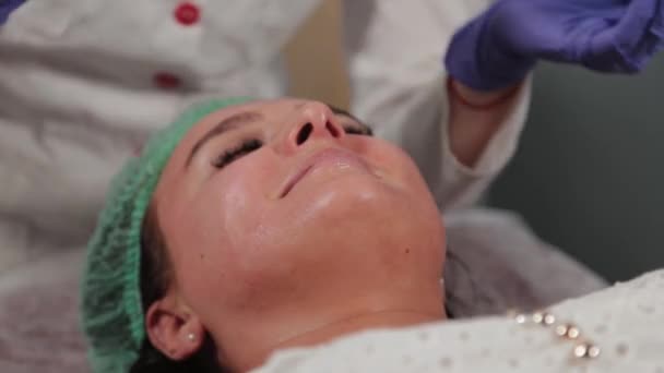 Cosmetóloga profesional haciendo limpieza facial ultrasónica al paciente. — Vídeos de Stock