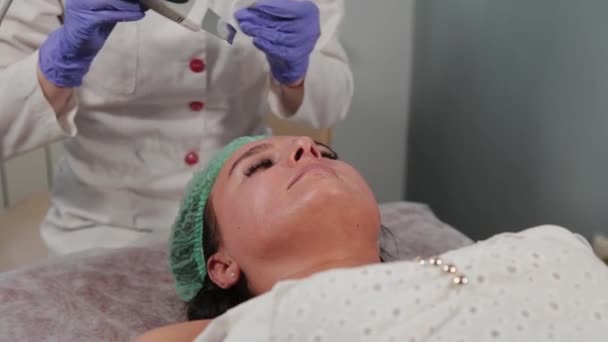 Profesyonel kozmetik uzmanı kadın hastaya ultrasonik yüz temizliği yapıyor.. — Stok video