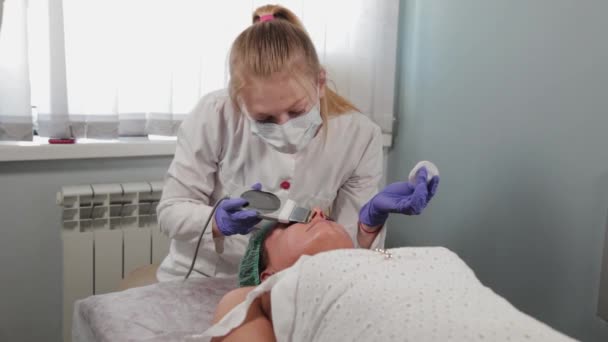 Donna cosmetologa professionista che fa pulizia del viso ad ultrasuoni al paziente. — Video Stock