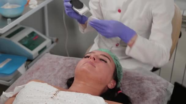 Cosmetologist profissional mulher fazendo limpeza facial ultra-sônica para paciente. — Vídeo de Stock