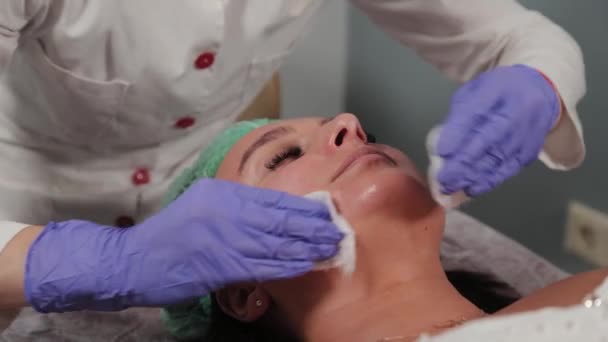 Professionele schoonheidsspecialiste wast het masker van het gezicht van een vrouw. — Stockvideo