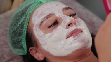 Elinde telefon, yüzünde maske olan bir kadın güzellik salonunda..