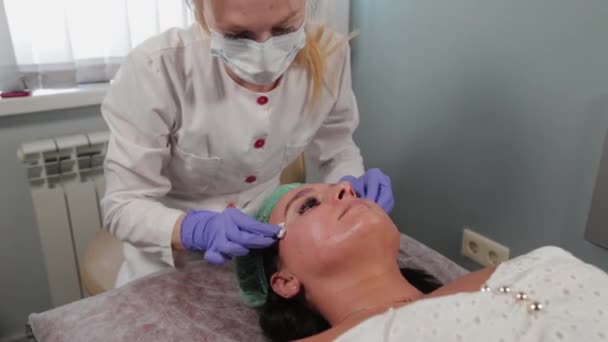 Profesionální kosmetička smyje masku z tváře ženy. — Stock video