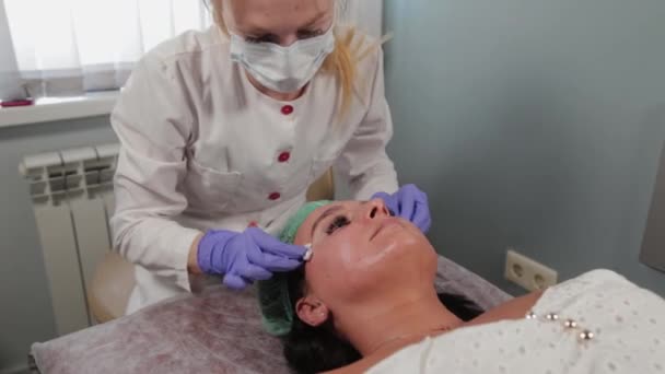 Esthéticienne professionnelle lave le masque sur le visage d'une femme. — Video