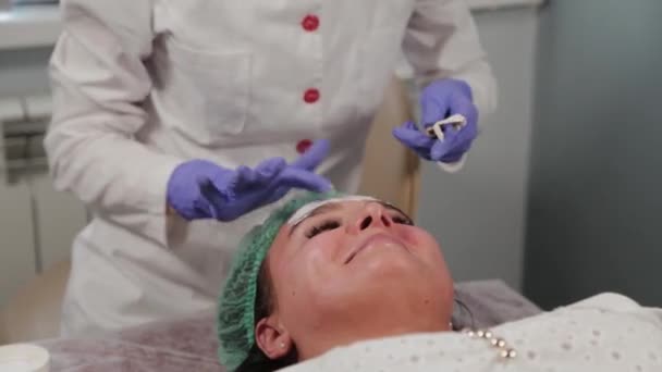 Esteticista profissional aplica uma máscara no rosto . — Vídeo de Stock