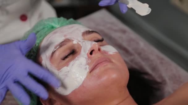 Professionelle Kosmetikerin trägt Maske auf das Gesicht auf. — Stockvideo