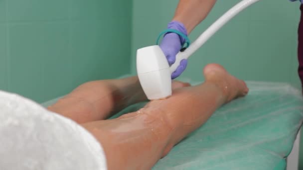 Esteticista hace depilación láser en las piernas. — Vídeo de stock