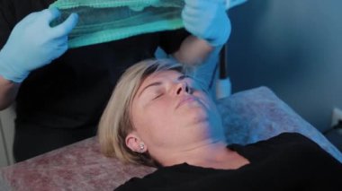 Güzellik uzmanı bir kadına yüz masajından önce şapka takar..