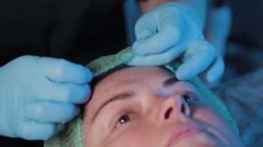 Güzellik uzmanı bir kadına yüz masajından önce şapka takar..