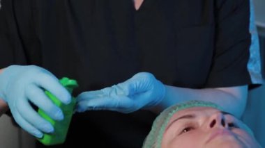 Profesyonel güzellik uzmanı mavi lastik eldivenleri antiseptikle tedavi ediyor.
