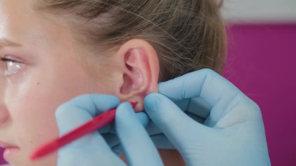 Vrouw arts voert oor piercing procedure voor meisje. — Stockvideo