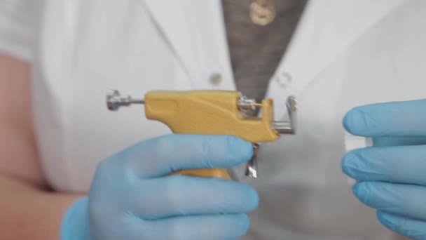 Kobieta lekarz przygotowuje przyrząd do kolczykowania ucha. — Wideo stockowe
