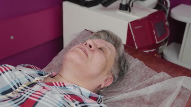 Idős nő papillómákkal az arcán az orvosi központban.. — Stock videók