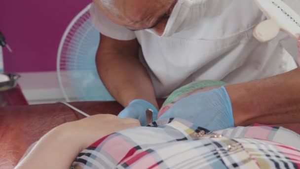 Médico varón elimina papilomas de una mujer anciana con un bisturí eléctrico. — Vídeo de stock