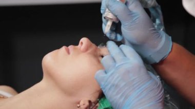 Kalıcı bir makyöz, bir kadının göz kapaklarına dövme yaptırır..