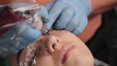 Kalıcı bir makyöz, bir kadının göz kapaklarına dövme yaptırır..