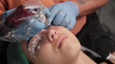 Kalıcı bir makyöz, bir kadının göz kapaklarına dövme yaptırır..