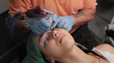 Kalıcı bir makyöz, bir kadının göz kapaklarına dövme yaptırır..