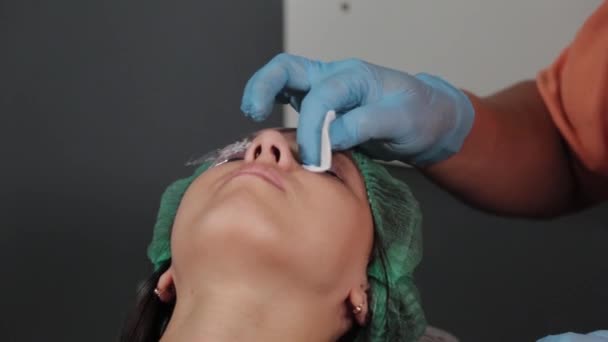 En permanent makeupartist tatuerar sig på ett kvinnans övre ögonlock. — Stockvideo