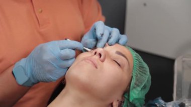 Kalıcı bir makyöz, bir kadının göz kapaklarına dövme yaptırır..