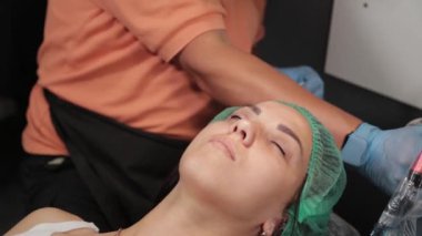 Kalıcı bir makyöz, bir kadının göz kapaklarına dövme yaptırır..