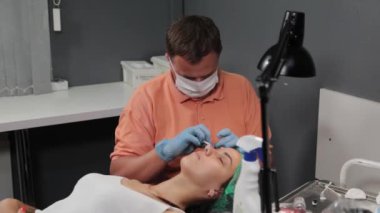 Kalıcı bir makyöz, bir kadının göz kapaklarına dövme yaptırır..