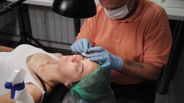Постоянный визажист делает татуировку на верхних веках женщины. — стоковое видео