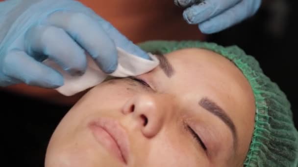 Kozmetikus használ kis pamut tampon eltávolítására festék szemhéjak női ügyfél egy szépségszalonban. — Stock videók