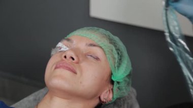 Kalıcı bir makyöz, bir kadının göz kapaklarına dövme yaptırır..