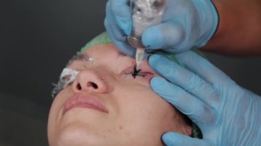 Kalıcı bir makyöz, bir kadının göz kapaklarına dövme yaptırır..