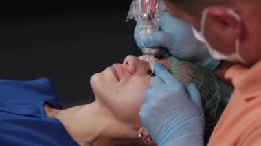 Kalıcı bir makyöz, bir kadının göz kapaklarına dövme yaptırır..