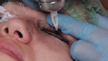 Kalıcı bir makyöz, bir kadının göz kapaklarına dövme yaptırır..