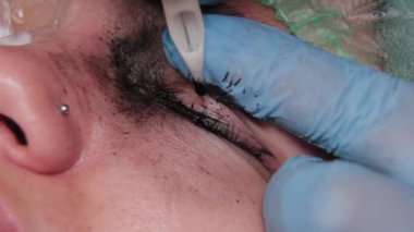 Kalıcı bir makyöz, bir kadının göz kapaklarına dövme yaptırır..